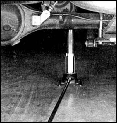 При поднятии задней части автомобиля – под балку заднего моста.