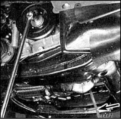 21. Отверните болт коленвала, зафиксировав (стрелка) венец маховика (или удерживая болт диска…