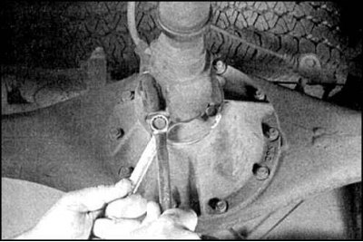 3. Удерживая болты, отверните четыре гайки крепления фланца заднего вала.